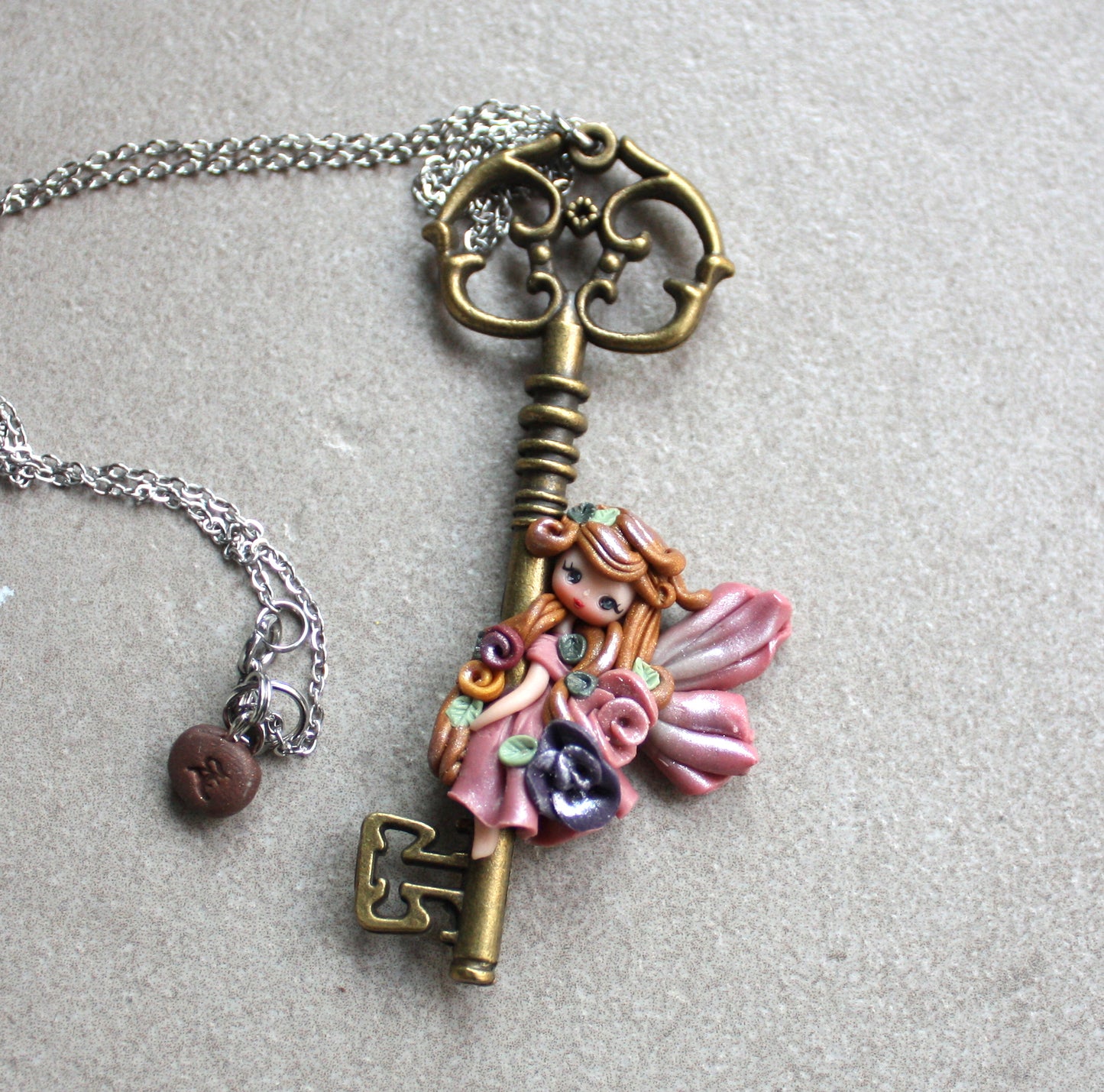 Collana in acciaio inox con chiave bronzata e fatina in fimo